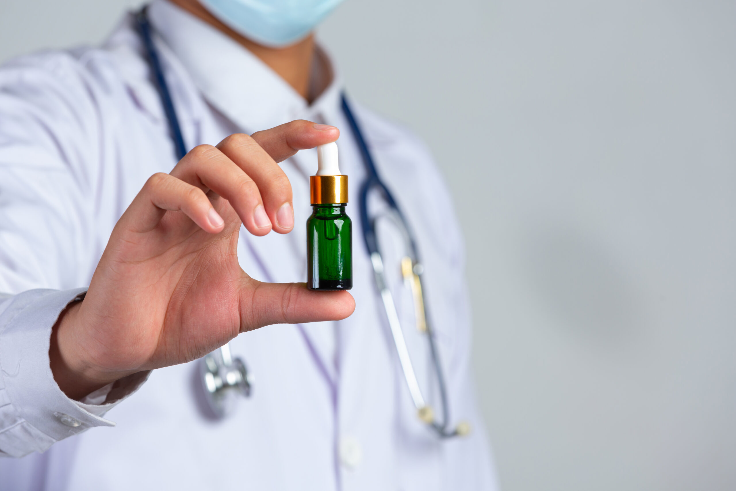 close up picture medical doctor holding bottle cannabis oil white wall scaled